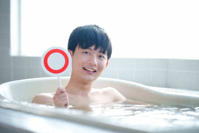 お風呂でマルの札を上げる男性